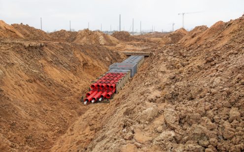 A 3D visualization of a duct bank system being installed in an open trench. 
