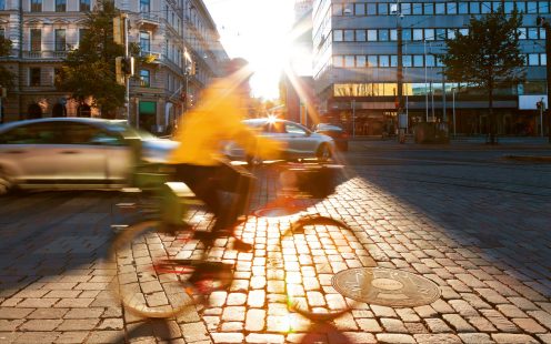 A cyclist rides by a manhole cover featuring the Pipelife logo.