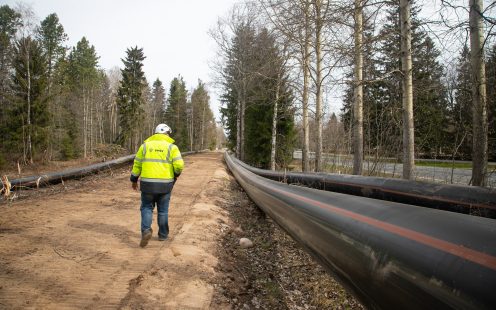 An installer walking along HDPE pressure pipes laid on the ground.