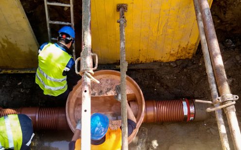 Three installers in an open trench setting up a PRO manhole on a rehabilitated sewer pipe.