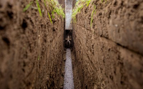 A close-up view of a field drainage pipe being laid underground