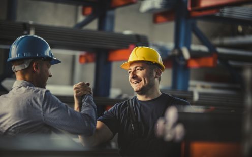 Happy metal worker greeting his manager in aluminum mill.