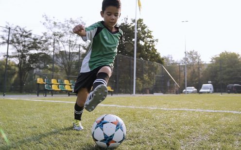 Boy playing soccer outdside on football pitch