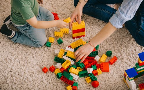 Cropped view of mom and son playing with toy blocks on carpet