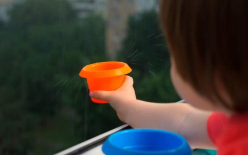 Kid play catching rain drops with toy can. Montessori background. Little girl play with rain. Rainy spring weather joy under rain drops, life health. Happiness, nature, childhood. Stay at home concept