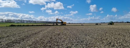 A wide-angle view of a freshly ploughed field with an excavator working in the background | Pipelife