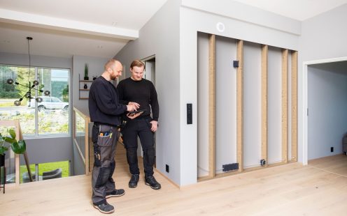 Two electricians standing next to a wall with several Powerline wall boxes installed | Pipelife