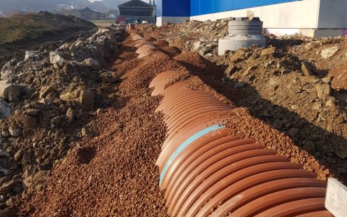 Large-diameter stormwater retention pipes installed next to a production plant building | Pipelife