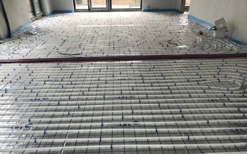 Two installers carrying a prefabricated underfloor heating mat to the installation site | Pipelife