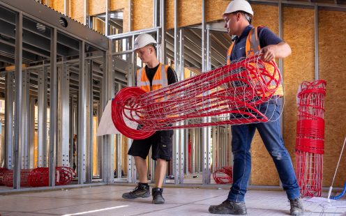 Two installers carrying a prefabricated underfloor heating mat to the installation site | Pipelife