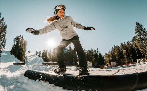 A young girl on a snowboard slides over an HDPE rail | Pipelife