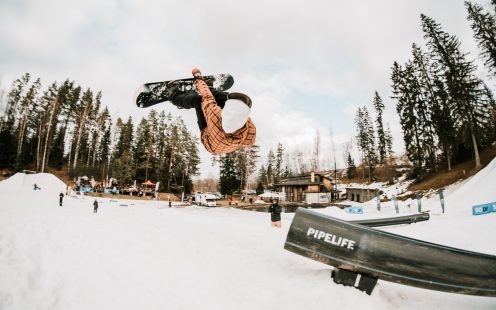 A snowboarder performing a flip in the air next to a Pipelife HDPE pipe | Pipelife