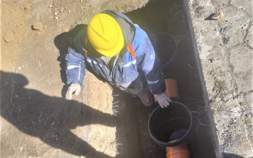 Worker standing in a shallow trench next to a Pragma pipe and two inspection chambers | Pipelife
