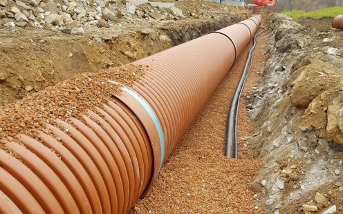Storage sewer system from large-diameter pipes and fittings set up in a shallow trench next to the concrete plant | Pipelife