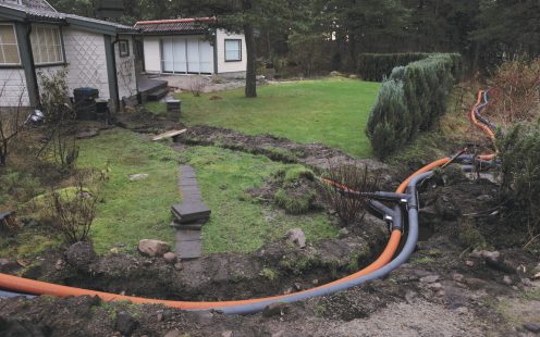 Two Isoterm pipes at a shallow trench next to two holiday homes and a forest | Pipelife