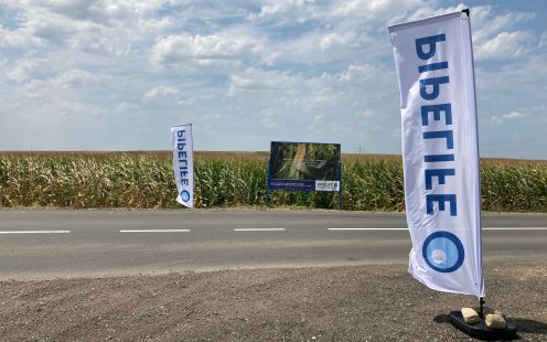 Two Pipelife flags and an informative signpost next to the road passing the irrigated cornfield | Pipelife