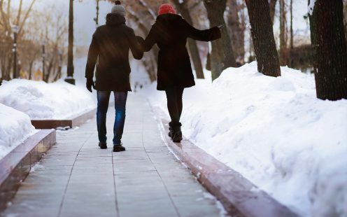 Couple walking through a snowy winter park