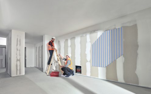 Two installers setting up a wall heating system.