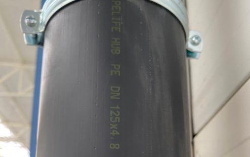 A close-up of a black Pipelife's roof drainage pipe, vertically  installed in a building.