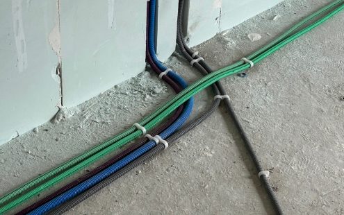 A close-up of six prewired conduits in three different colors laid on a floor | Pipelife