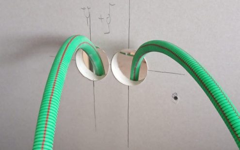A close-up of two green halogen-free prewired conduits with a red marking line | Pipelife