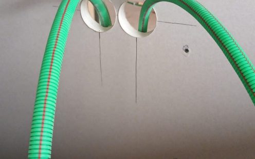 A close-up of two green halogen-free prewired conduits with a red marking line | Pipelife
