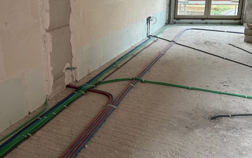 Prewired conduits in five different colors laid on a floor in a building | Pipelife