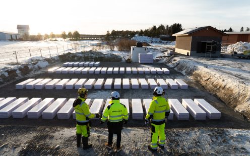 Three men wearing work attire and helmets standing next to a dug-out area prepared for installation.