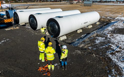 Three installers standing next to four recently installed water storage tanks.