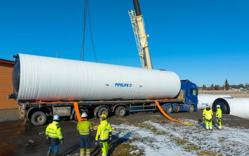 A truck carrying a large water supply tank parked next to the installation pit.