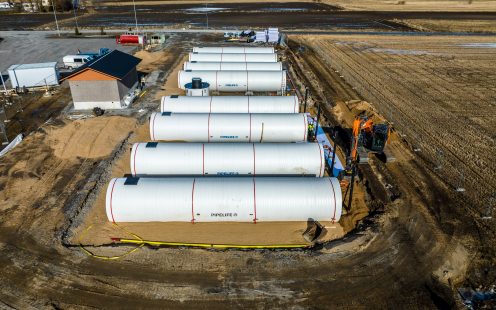An aerial photo of eight large, white water storage tanks laid in an open trench.