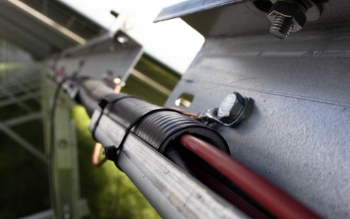 A close-up of Pipelife's prewired photovoltaic electrical conduit installed at the back of a solar panel.