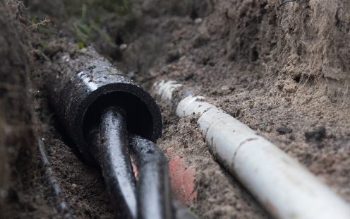 An unearthed black PE cable protection pipe with two cables inside it.