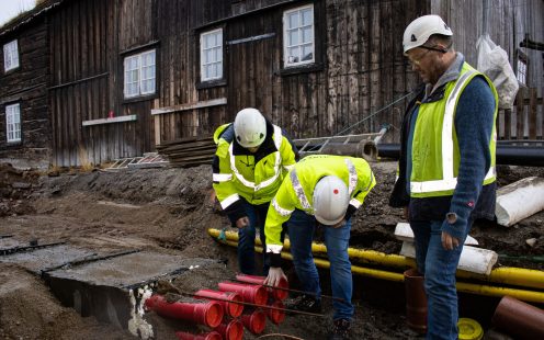 Three installers standing next to a duct bank laid in an open trench.