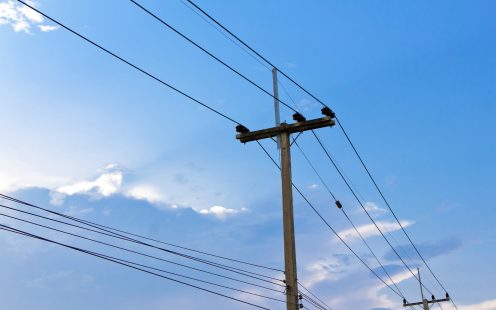 Electric pole power lines and wires with blue sky.