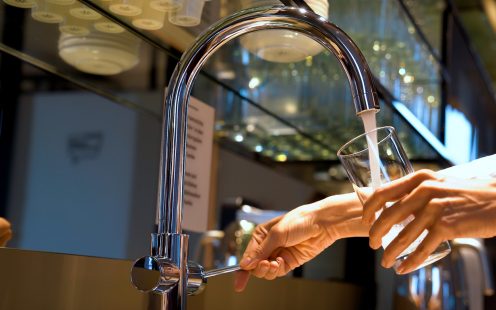 A woman is pouring tap water into a glass.