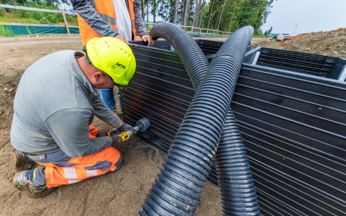 Construction worker drilling an opening into a cable duct chamber