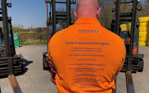 A picture containing workers on production site wearing T-Shirts with safety rules written on the backs.