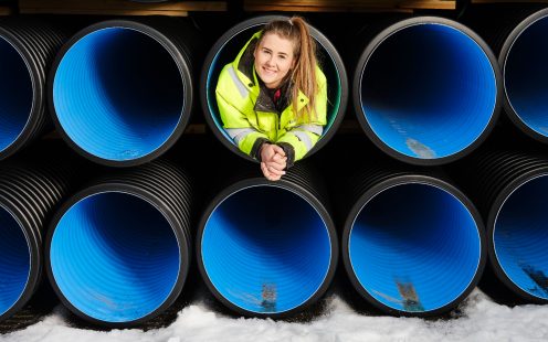 Employee sits inside pipes smiling | Pipelife International